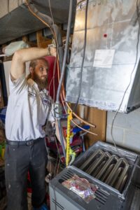 Elliot, a tech at One Hour Air working on a heater coil for an AC Unit