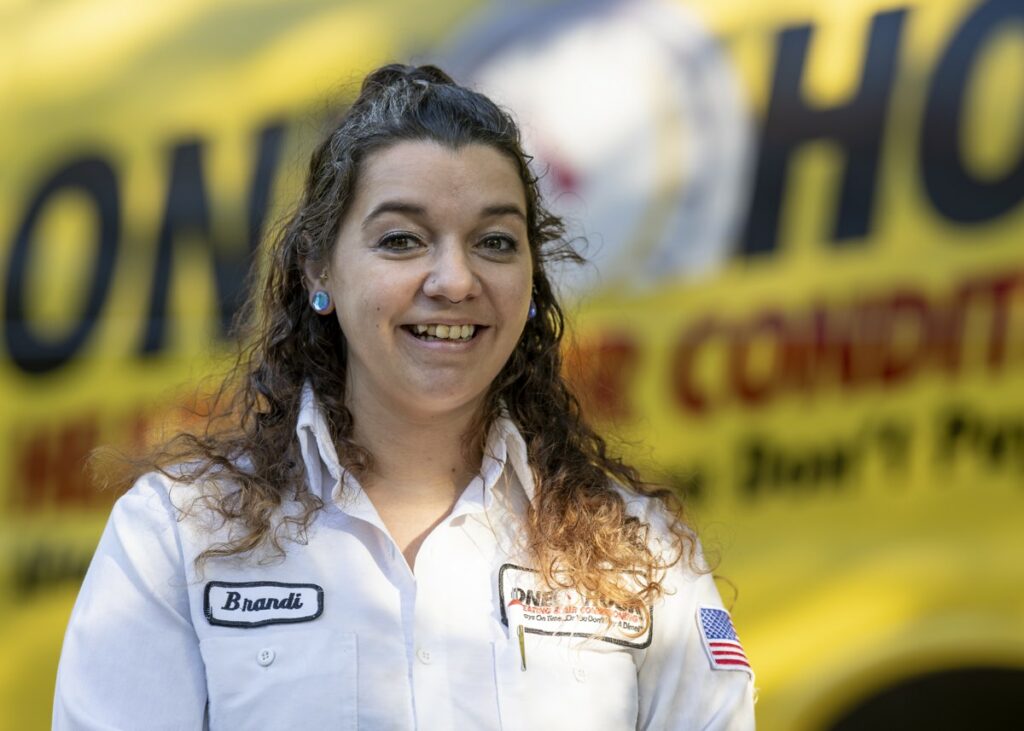 Brandi an AC repair tech in front of a One Hour service van How Do I Know If My AC Capacitor Is Blown?